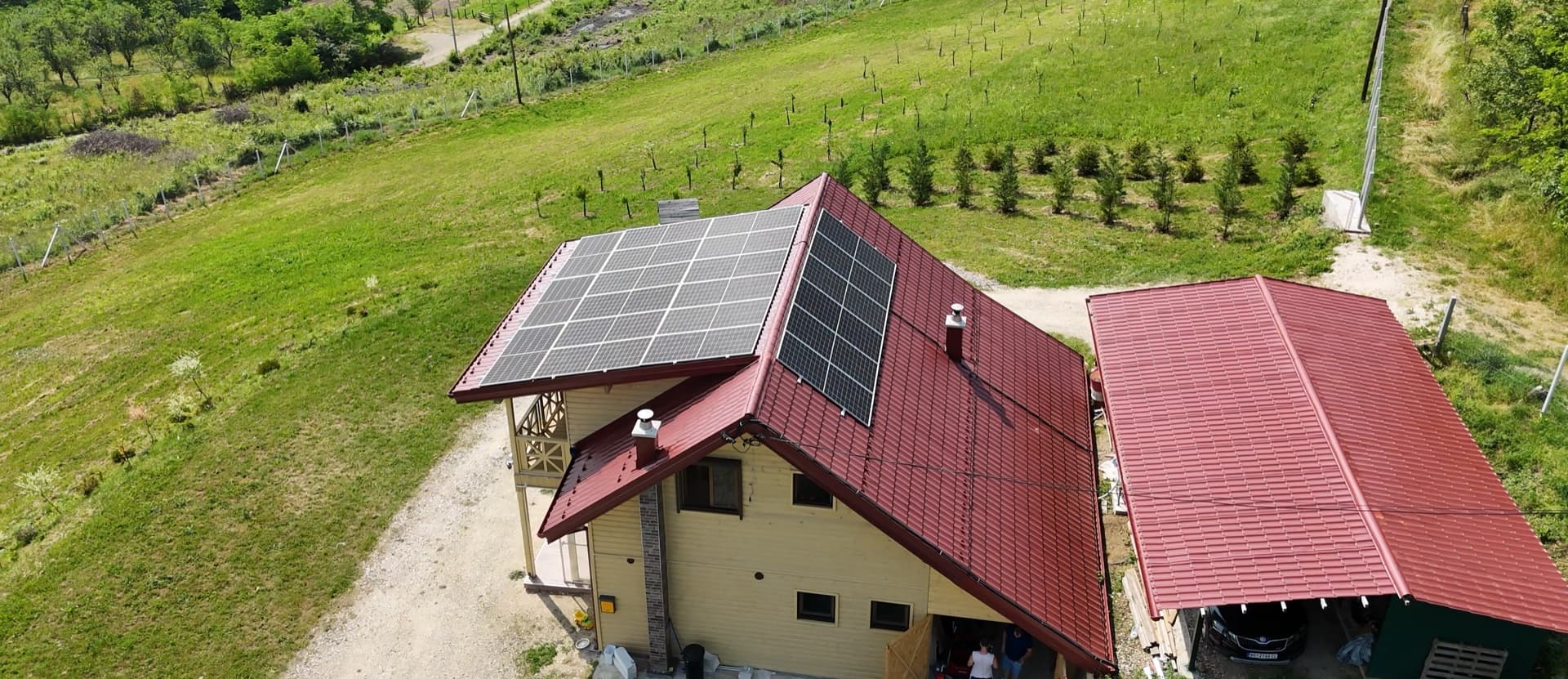 Solarni paneli na crvenom krovu kuće u prirodi — referentni 10 kW On-Grid Max sistem