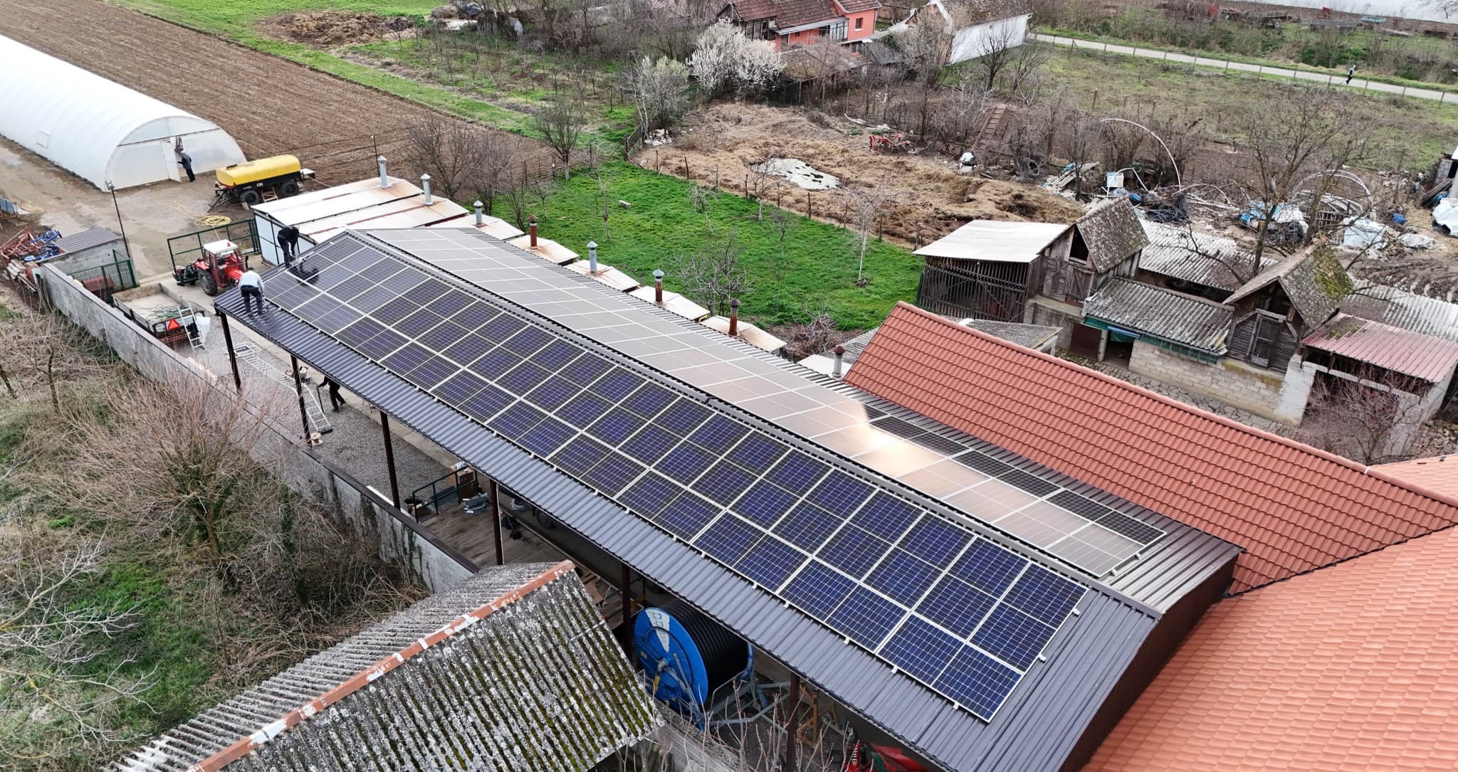 Dugačak niz solarnih panela na krovu objekta na farmi — referentni 10 kW On-Grid Max sistem